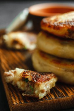 Ahşap bir tahtanın üzerinde patates turtası ketçaplı çatal bıçak takımı ve tahtadan yapılmış sarımsaklı. Koyu beton arkaplan, kenar görünüm makro