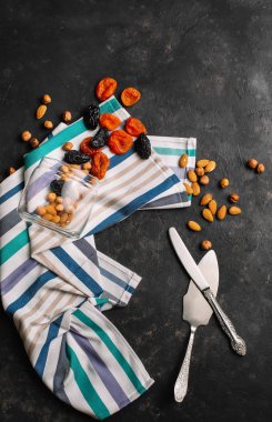 Cam kavanoz, kurumuş kayısı, kuru erik ve fındık. Koyu arkaplanda üst görünüm