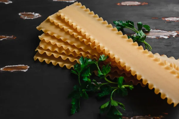 Raw lasagna ingredients and pasta products background with copy space. Top view and background of vegetables on a dark background