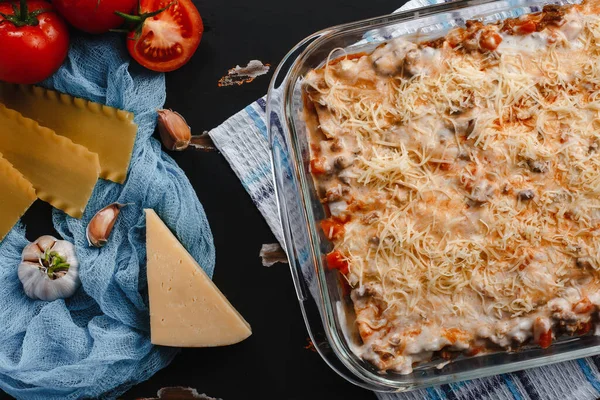 Raw lasagna ingredients and pasta products background with copy space. Top view and background of vegetables on a dark background
