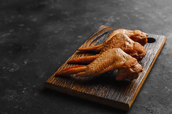 Smoked chicken wings on a wooden table with a towel and a dark background top view