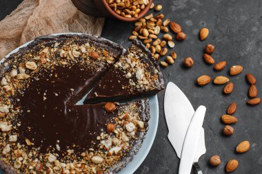 Çikolatalı pasta, çikolatalı pasta, fındıklı tatlı. Kesik bir parça. Kızarmış fıstık, badem ve fındık. Karanlık arka planda. Yukarıdan manzara. Yandan manzara. Metin için boşluk.