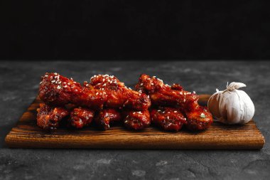 Barbekü soslu ızgara tavuk kanadı ve sehpanın üzerinde susam ve maydanoz. Metin için boşluk olan üst görünüm. Koyu arkaplanda nefis bir bira aperatifi..