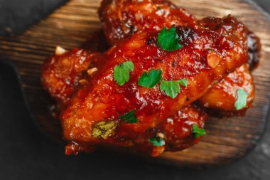Barbekü soslu ızgara tavuk kanadı ve sehpanın üzerinde susam ve maydanoz. Metin için boşluk olan üst görünüm. Koyu arkaplanda nefis bir bira aperatifi..