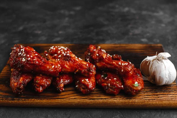 Barbekü soslu ızgara tavuk kanadı ve sehpanın üzerinde susam ve maydanoz. Metin için boşluk olan üst görünüm. Koyu arkaplanda nefis bir bira aperatifi..