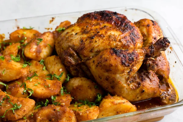 Patates ve otlarla bütün tavuğu köy usulü pişirdim. Üst görünüm, arka planda yan görünüm. Yakın plan ve orta plan. Metin için boşluk.