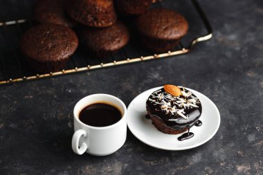 Çikolatalı kekler, muzlu kekler, fındıklar ve bir fincan kahve. Siyah bir masada ve karanlık bir arkaplanda. Üst manzara, yan manzara. Yakın plan ve orta plan. Metin için boşluk.