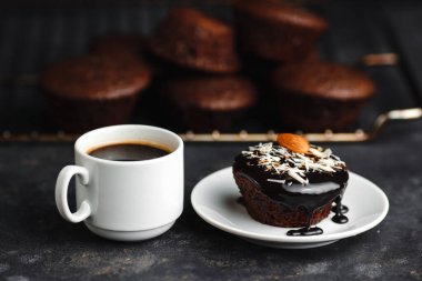 Çikolatalı kekler, muzlu kekler, fındıklar ve bir fincan kahve. Siyah bir masada ve karanlık bir arkaplanda. Üst manzara, yan manzara. Yakın plan ve orta plan. Metin için boşluk.
