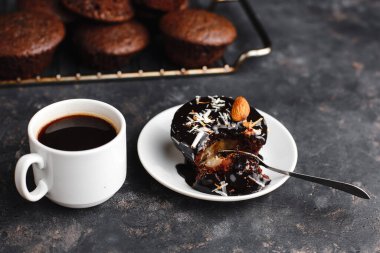 Çikolatalı kekler, muzlu kekler, fındıklar ve bir fincan kahve. Siyah bir masada ve karanlık bir arkaplanda. Üst manzara, yan manzara. Yakın plan ve orta plan. Metin için boşluk.