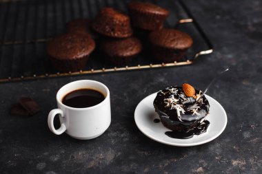 Çikolatalı kekler, muzlu kekler, fındıklar ve bir fincan kahve. Siyah bir masada ve karanlık bir arkaplanda. Üst manzara, yan manzara. Yakın plan ve orta plan. Metin için boşluk.