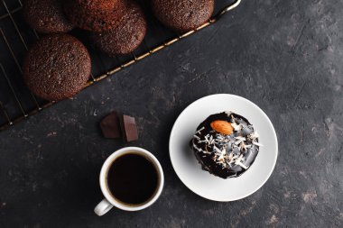 Çikolatalı kekler, muzlu kekler, fındıklar ve bir fincan kahve. Siyah bir masada ve karanlık bir arkaplanda. Üst manzara, yan manzara. Yakın plan ve orta plan. Metin için boşluk.