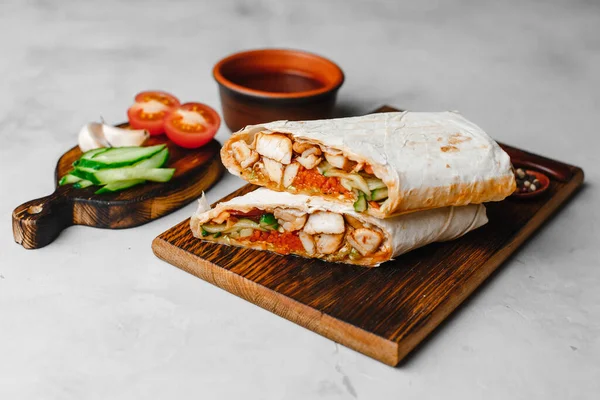 Ev yapımı Shawarma, burrito, sebzeli tavuk dürümü ve sos. İçindekilerin temiz bir alana sahip üst görünümü.