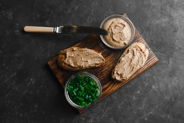 Fresh homemade chicken liver pate with herbs. Bread bruschetta with liver pate with onion, cucumber and radish. Top view, side view on a dark background. space for text.