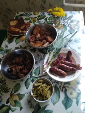 Tabaklarında tabaklar, sosisler ve ızgara sebzeler olan şenlik masası.