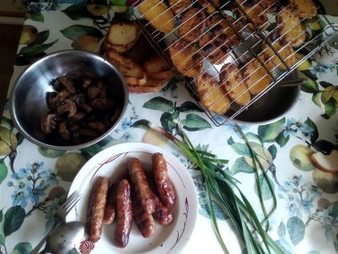 Tabaklarında tabaklar, sosisler ve ızgara sebzeler olan şenlik masası.