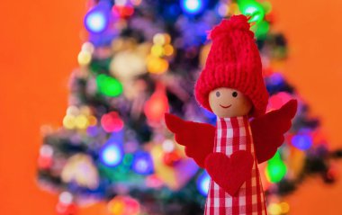 Noel ağacının arka planında kırmızı örülmüş şapkalı melek. Yeni yıl ve Noel arkaplanı.