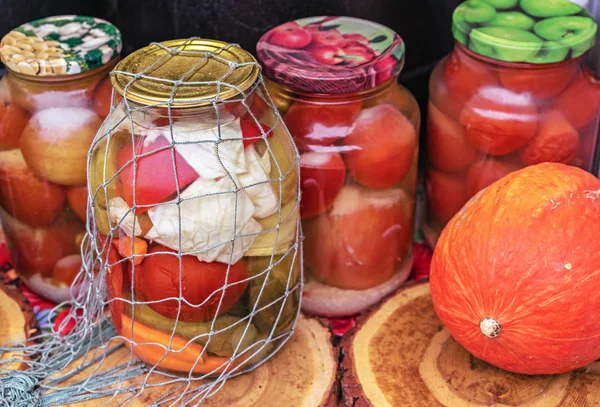 Canned vegetables in glass jars. Pickled cucumbers and tomatoes. — Stock Photo, Image