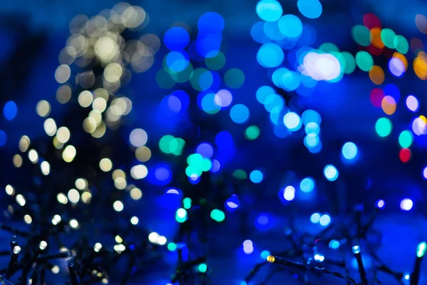 Defocused kerstslingers met kleurrijke gloed. Kerst achtergrond met veelkleurige bokeh. — Stockfoto