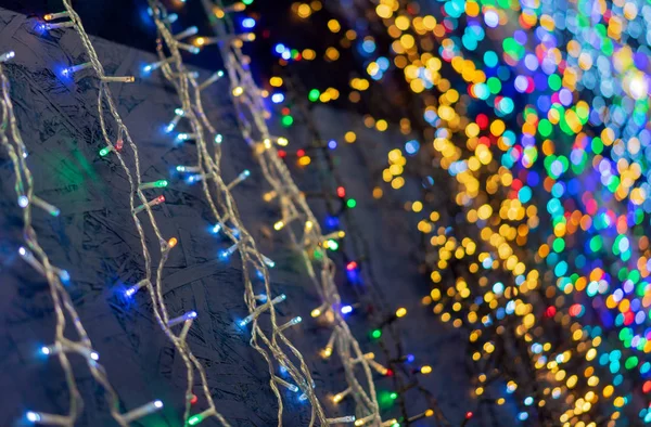 Defocused christmas garlands with colorful glow. Christmas background with multicolored bokeh. — Stock Photo, Image