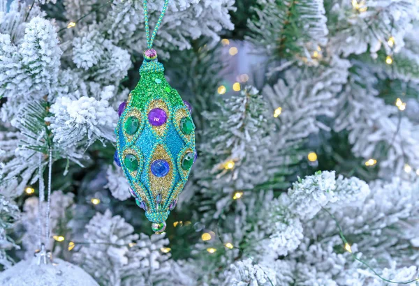 Juguete de Navidad verde con pedrería y lentejuelas en un árbol de Navidad nevado . — Foto de Stock