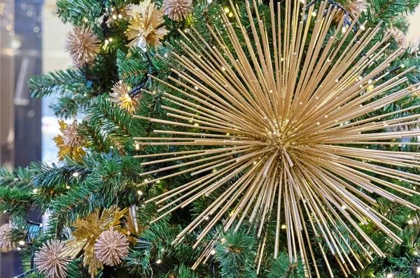 Kerstversiering in de vorm van een gouden vuurwerk op een kerstboom. — Stockfoto