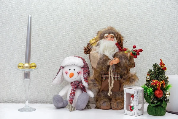 Leksaker jultomten och en snögubbe nära en liten julgran. — Stockfoto