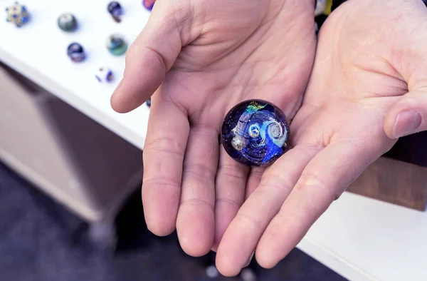 Glass ball with the image of the universe, stars and planets in the hands of man. The concept of a fragile world.