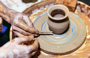 Profesyonel çömlekçi çömlek çarkında demlik yapar ve bir öğrenciye öğretir. Bir çömlekçinin elleri.