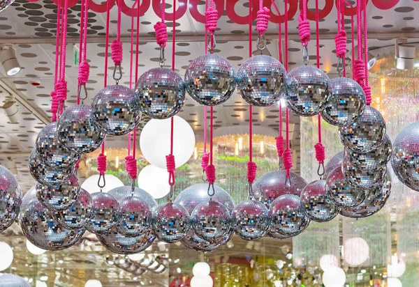 Disco balls hang on pink ropes. Background with a lot of disco balls.