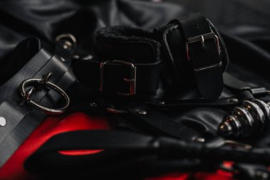 Fetiş için kırbaç ve kelepçe, karanlık arka planda bdsm oyunları