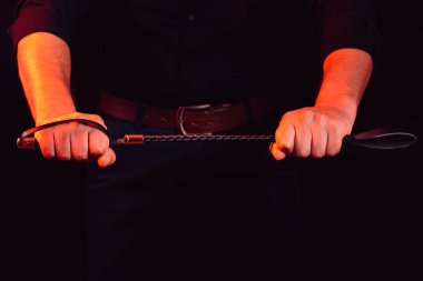 Elinde BDSM kırbacı olan yakışıklı bir adam.