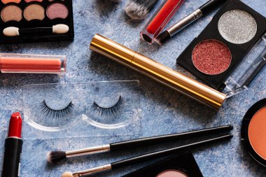 Çeşitli makyaj ürünleri, mavi arkaplanda fırçalar