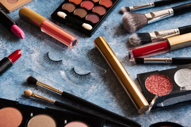 Çeşitli makyaj ürünleri, mavi arkaplanda fırçalar