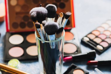 brushes for make-up are on the table, where lies decorative cosmetics