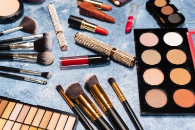 Çeşitli makyaj ürünleri, mavi arkaplanda fırçalar