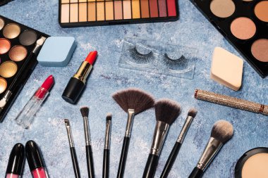 Çeşitli makyaj ürünleri, mavi arkaplanda fırçalar