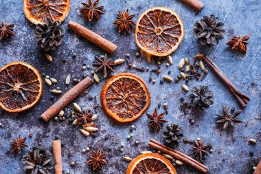Kurutulmuş portakal, tarçın çubukları, pembe biber, kakule, anason, mavi arka planda karanfil. Yukarıdan görünüşü