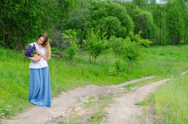 Kırsal yolda çayır çiçek sepeti ile güzel kız 