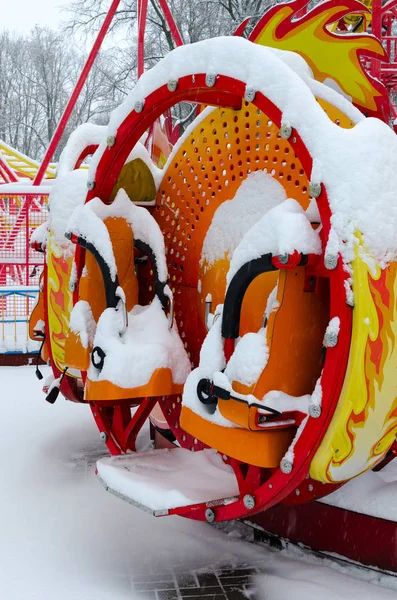 Atração infantil coberta de neve no parque de inverno durante a queda de neve — Fotografia de Stock