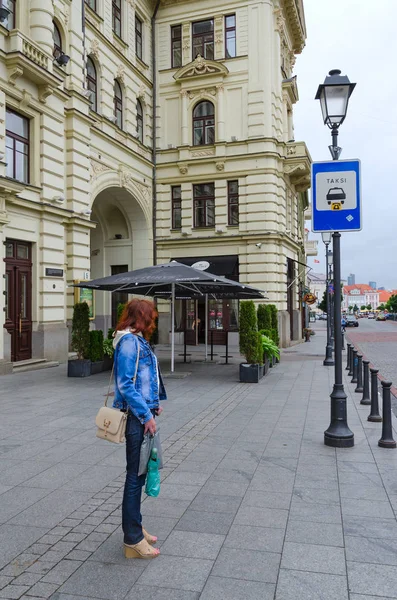 Chica se para en parada de taxi cerca de la Filarmónica Nacional de Lituania en el casco antiguo, Vilna, Lituania — Foto de Stock