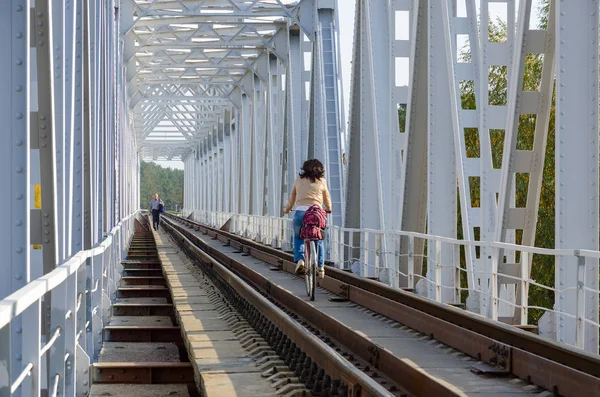 Mädchen fährt mit Fahrrad auf Eisenbahnbrücke über Fluss — Stockfoto