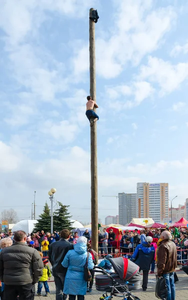 Genç adam için ödül ahşap ayağı üzerinde Shrovetide eğlence sırasında tırmanıyor — Stok fotoğraf