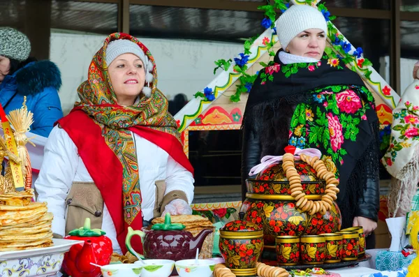 Twee vrouwen zijn aan tafel met pannenkoeken en geschilderde gebruiksvoorwerpen tijdens stuk festiviteiten — Stockfoto