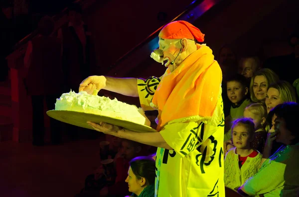 Ledsna clownen står i publiken bland åskådare och hålla stora födelsedagstårta — Stockfoto