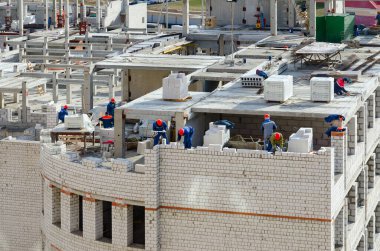 GOMEL, BELARUS - 21 Mart 2020: Dünya Sağlık Örgütü 'nün duyurduğu salgın sırasında yeni mikro bölgede okul inşaatında çalışan tanınmamış inşaatçılar, Gomel, Belarus