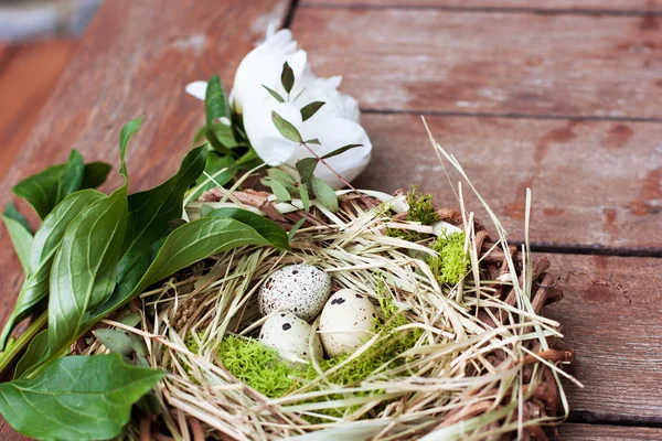 Üç bıldırcın yumurtası ve Şakayık ahşap arka plan üzerinde dekoratif yuva