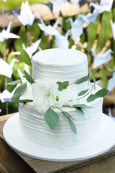 Wedding white cake decorated with flowers and eucalyptus on stand on green background — Stock Photo, Image