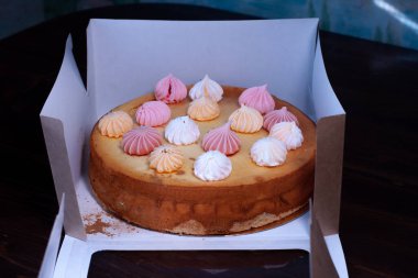 Tahta bir masanın üzerinde kremayla süslenmiş cheesecake.