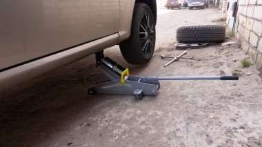 Arabadaki tekerlekleri değiştiriyorum. Arabayı krikoyla kaldırıyorum.