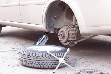 Arabadaki tekerlekleri değiştiriyorum. Arabayı krikoyla kaldırıyorum.